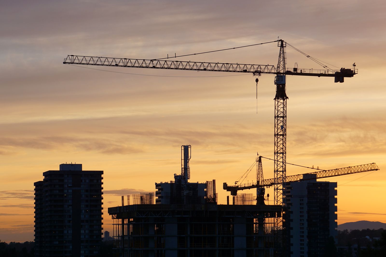 Tower crane silhouetted over a building under construction at dusk